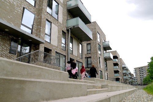 Image shows a family walking alongside a housing block.